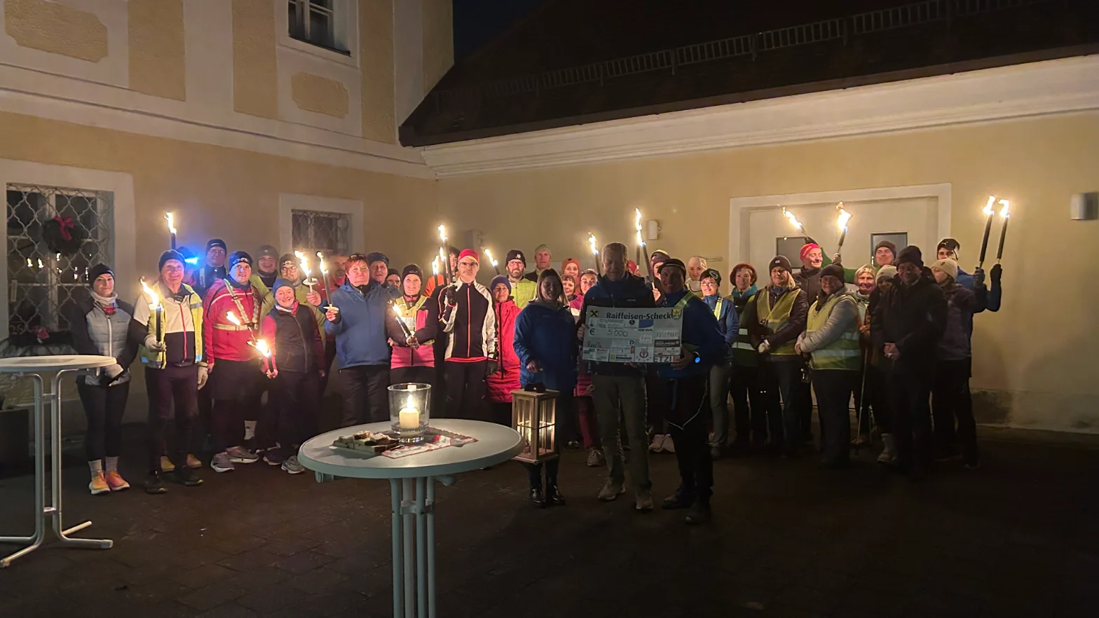 Teilnehmende des Friedenslicht-Marathons mit brennenden Fackeln beim gemeinsamen Abschluss