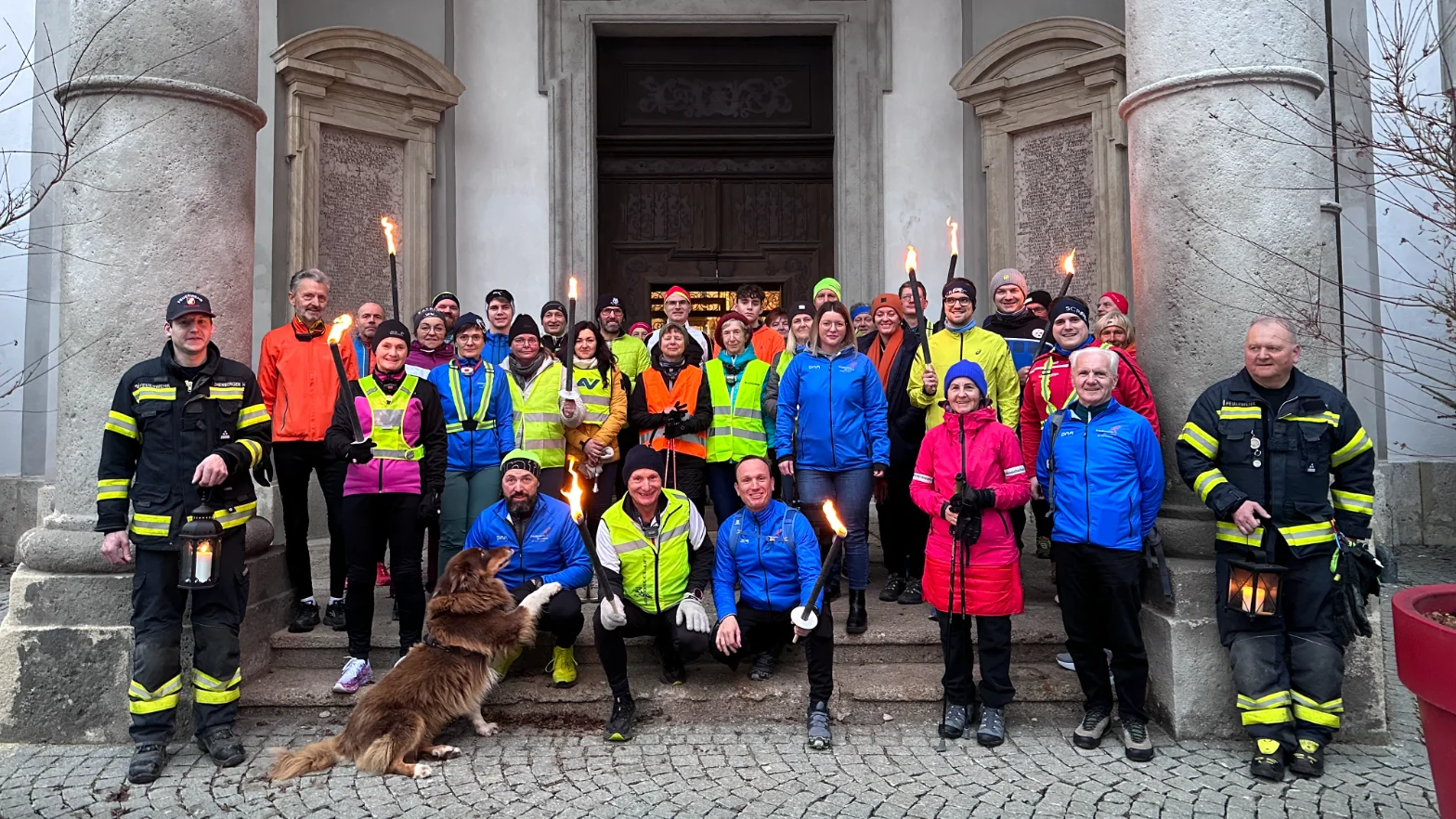Teilnehmende des Friedenslicht-Marathons mit Fackeln vor einer Kirche